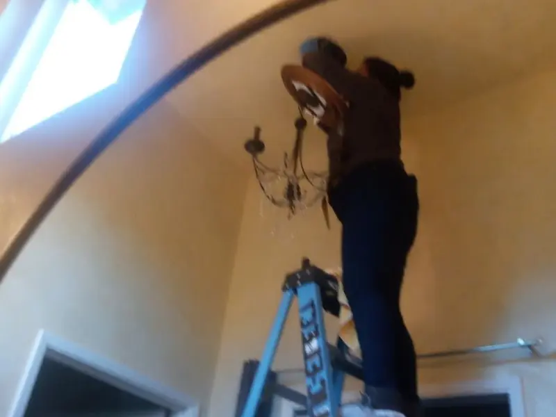 Electrician installing a chandelier in a St. James residence